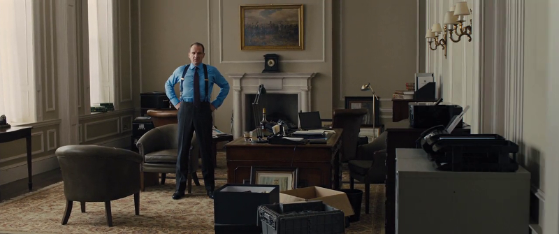 Gareth Mallory (played by Ralph Fiennes) stands awkwardly after M leaves his office in Skyfall (2012)