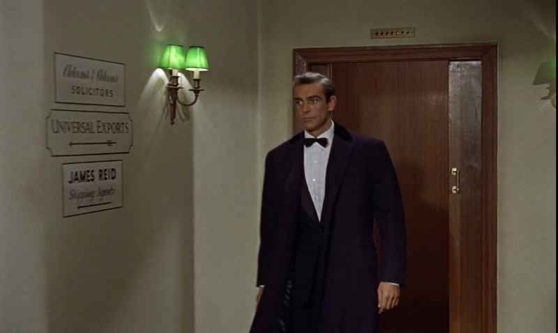 007 is shown walking into M's office, which has a Universal Exports sign on the outside