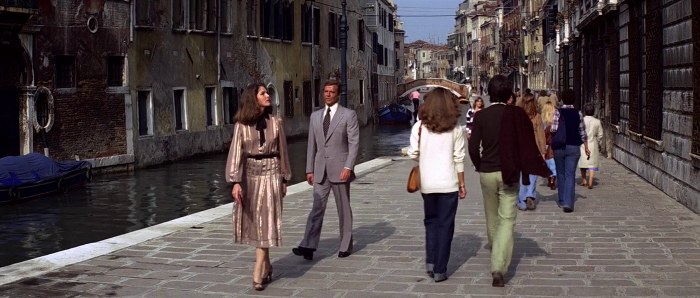 Holly Goodhead (Lois Chiles) and James Bond (Roger Moore) walk down a Venice street in Moonraker (1979) - 007 obviously embarrassed by her dress choice
