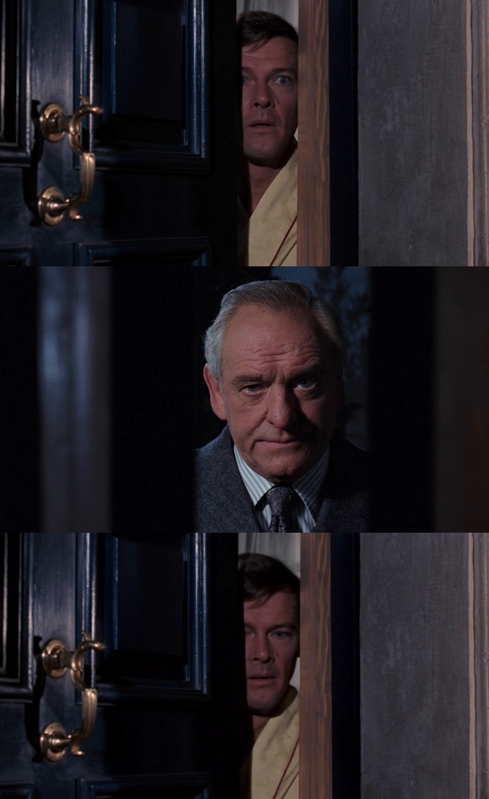 James Bond (Roger Moore) answers the door late night at his home only to find M (Bernard Lee) on the other side in Live and Let Die (1973)